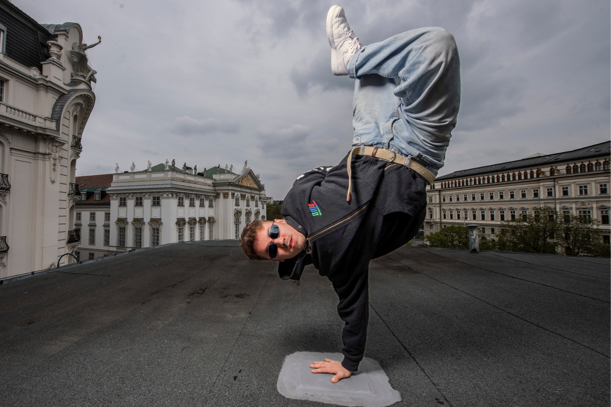 Heilmasseur Domenic Hacker bei einem Breakdance-Move auf dem Volkstheater in Wien – Bewegung als Ausdruck von Körpergefühl